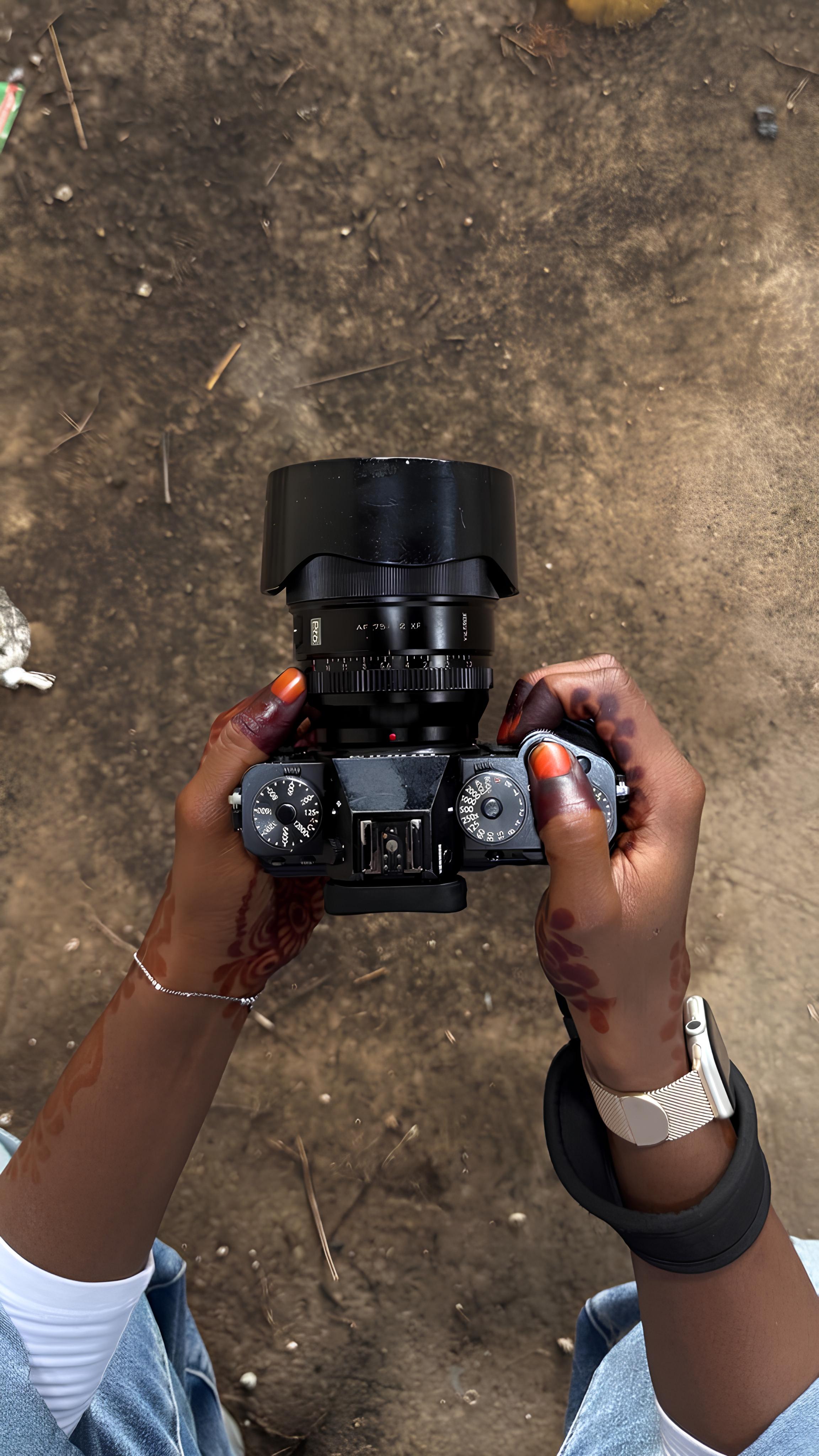 Hands holding a Fujifilm X-T mirrorless camera fitted with a Fujinon XF prime lens