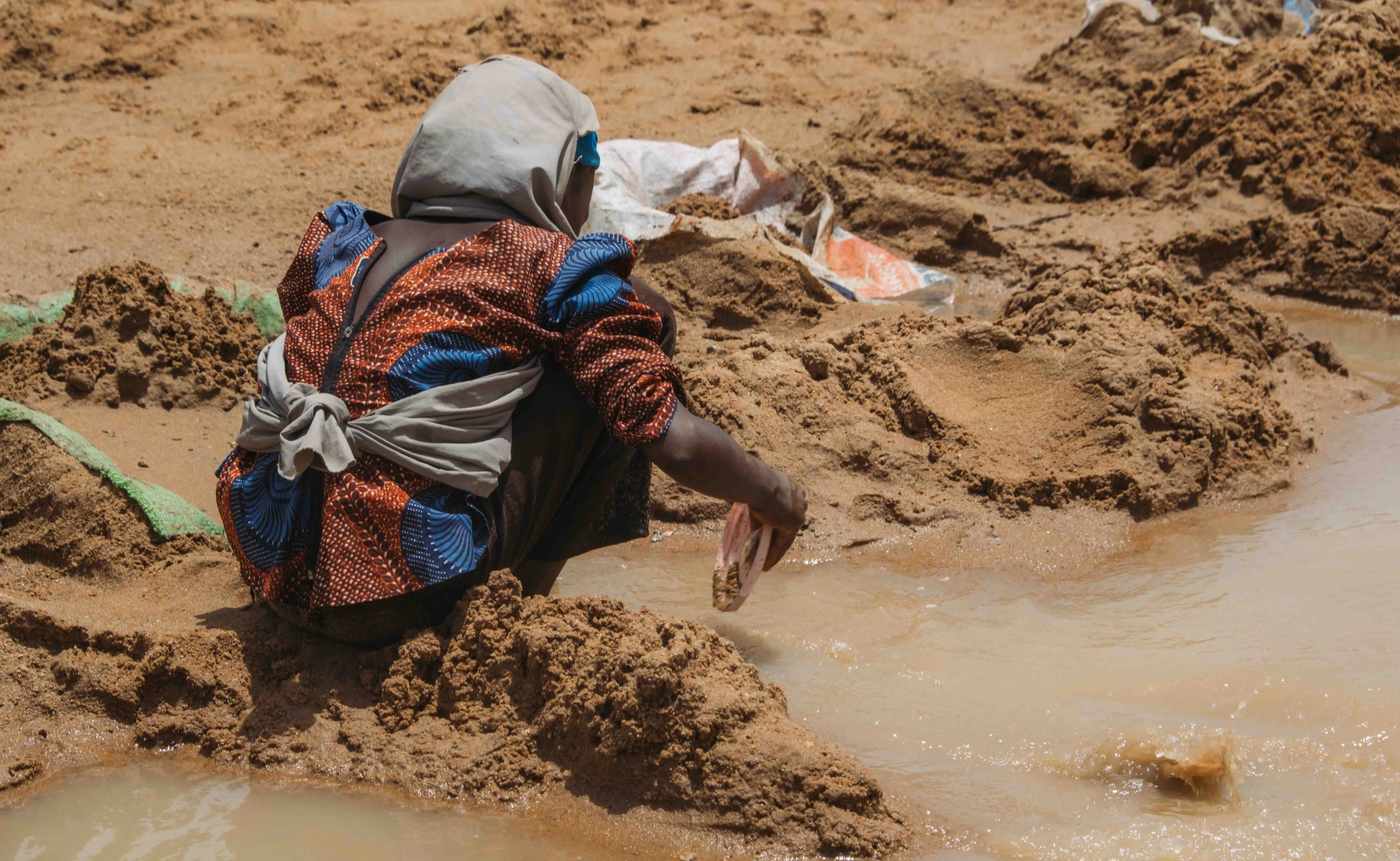 Close-up of hands sifting sediment through a woven basket