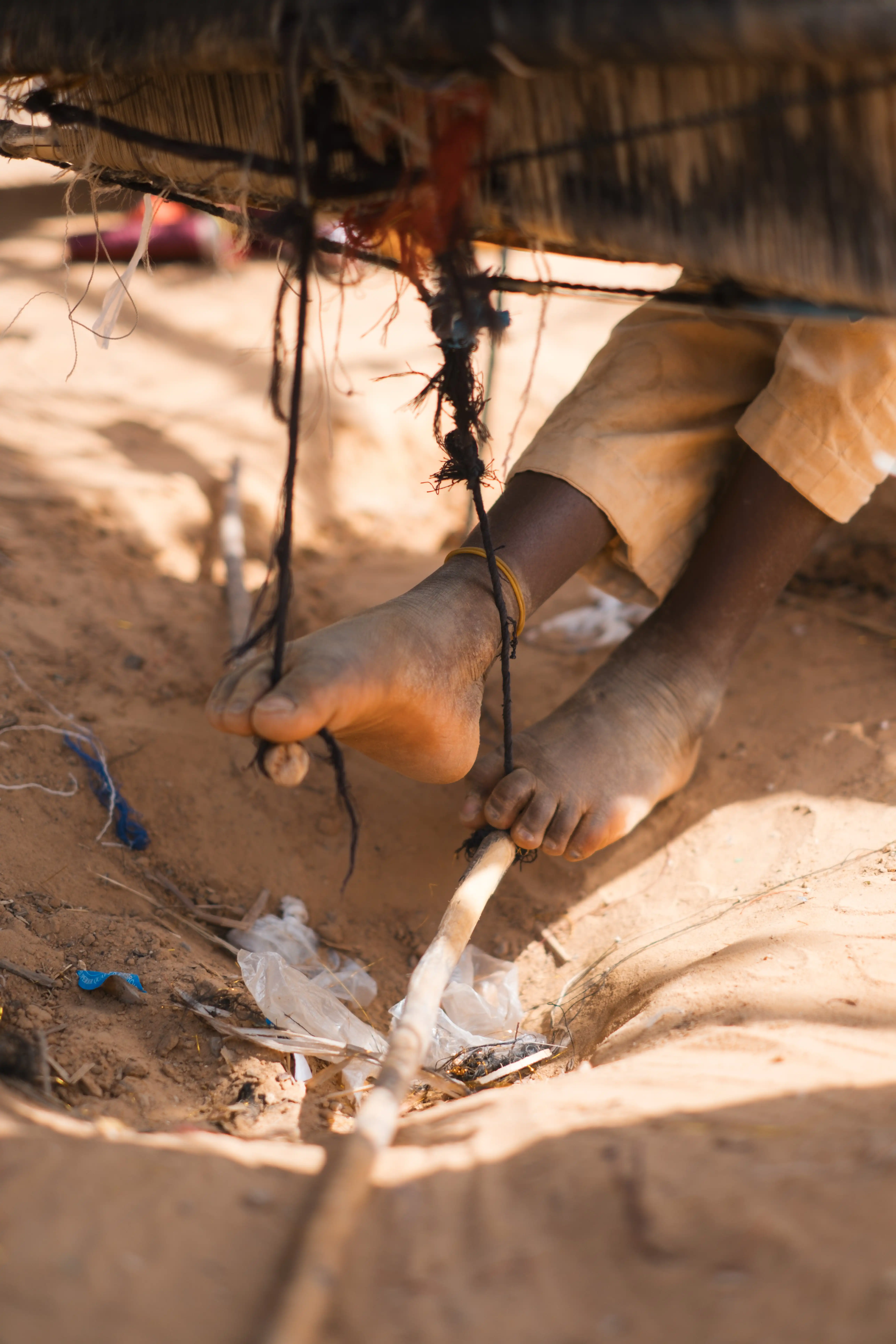 Weaver holding a spool of indigo thread beside the loom