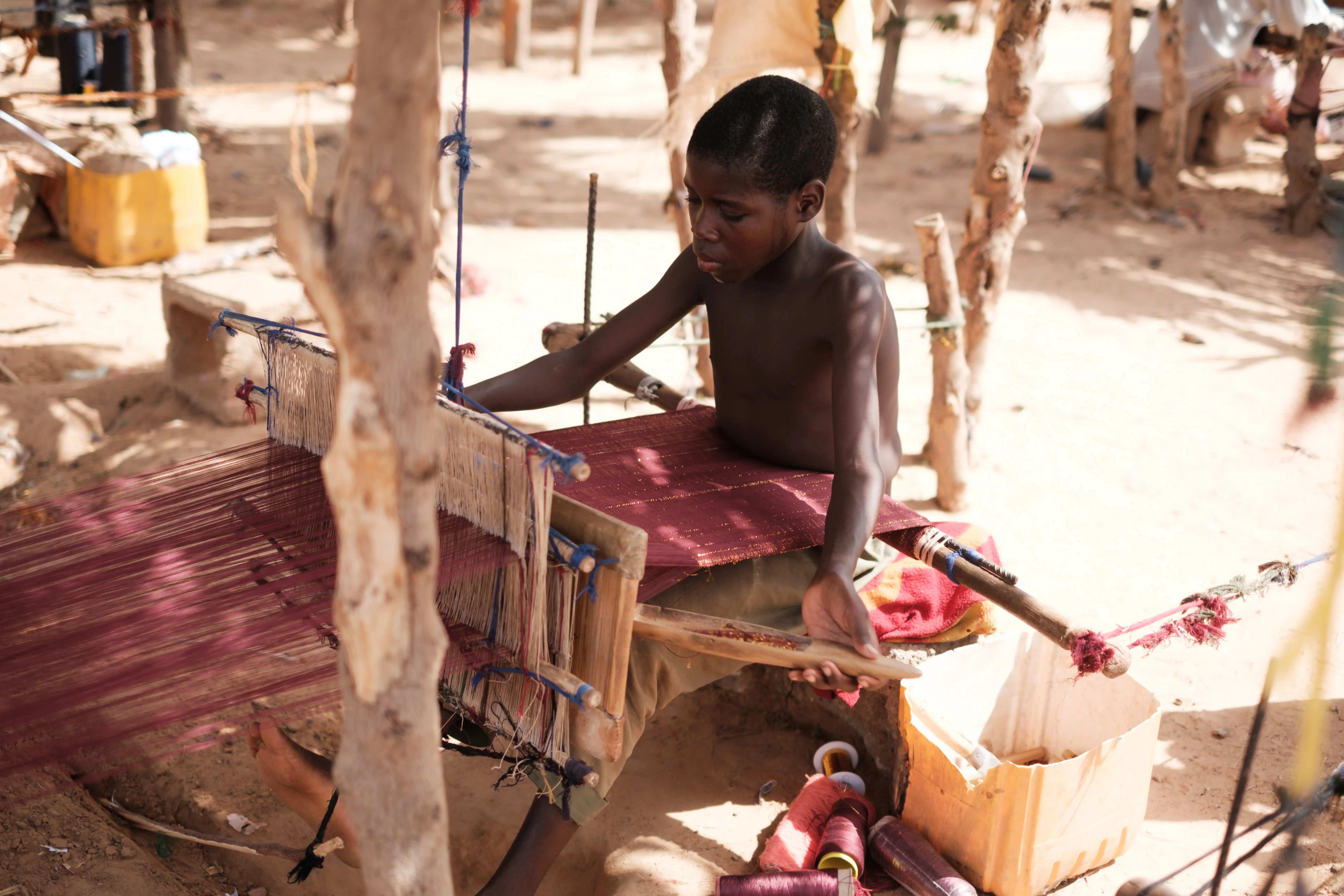 Kano weaver surrounded by vibrant textiles